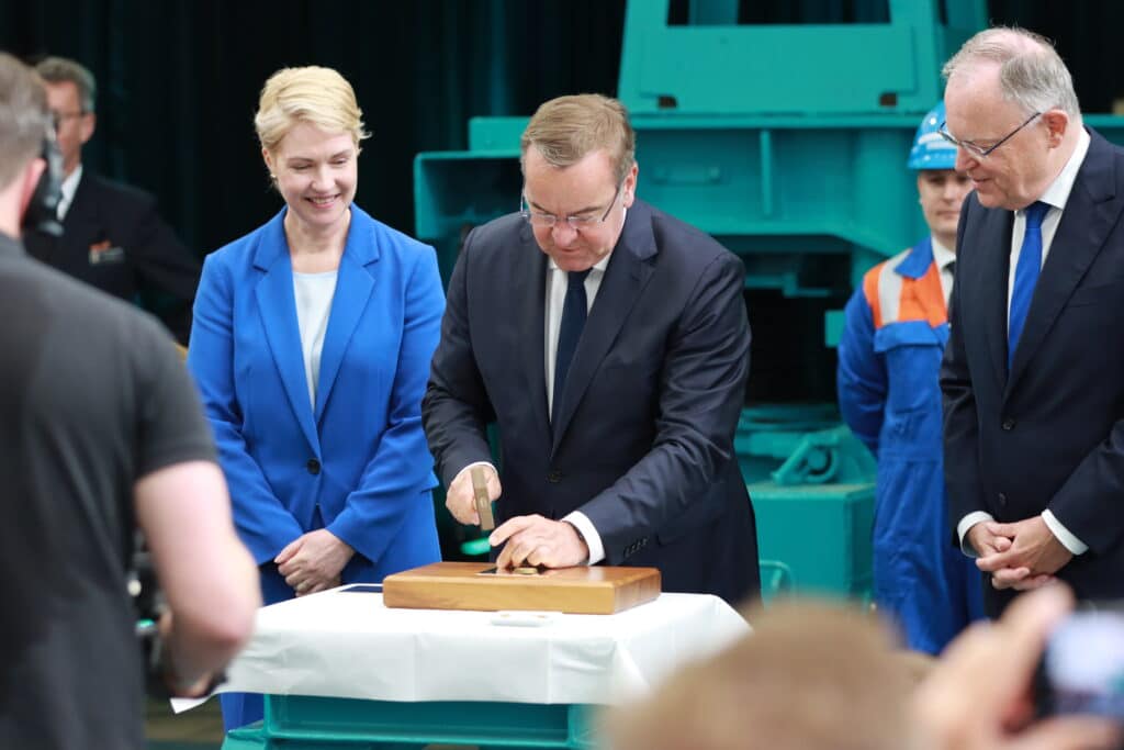 وزير الدفاع الألماني بيستوريوس يعلق عملة معدنية على لوح، كجزء من مراسم وضع عارضة الفرقاطة الجديدة.